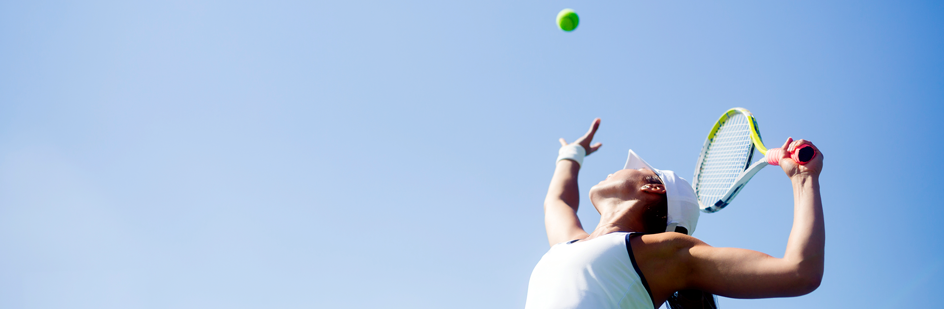 photo of woman throwing ball in the air to serve